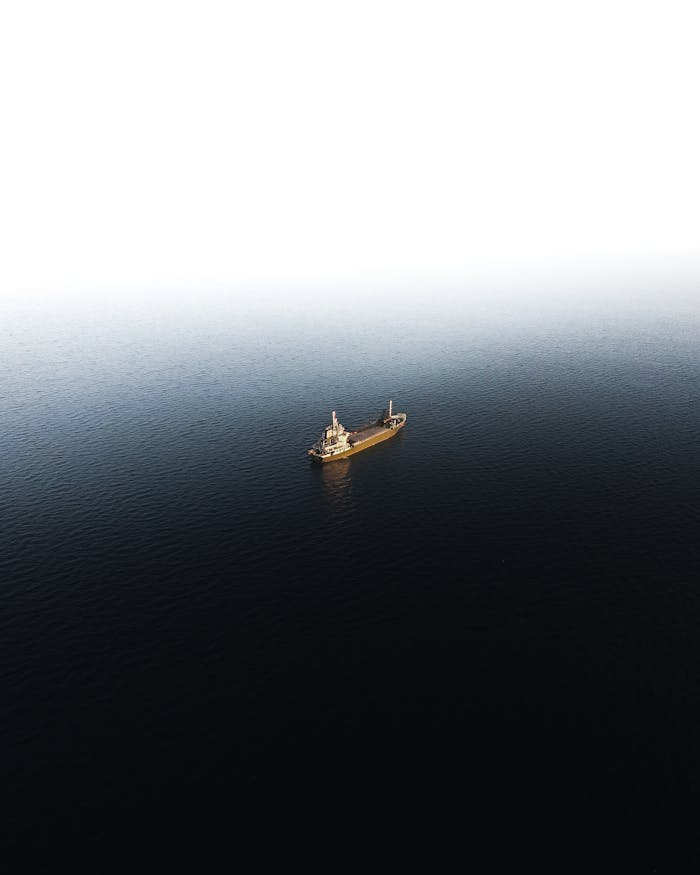 Aerial photograph of a solitary cargo ship navigating calm, expansive ocean waters in Japan.